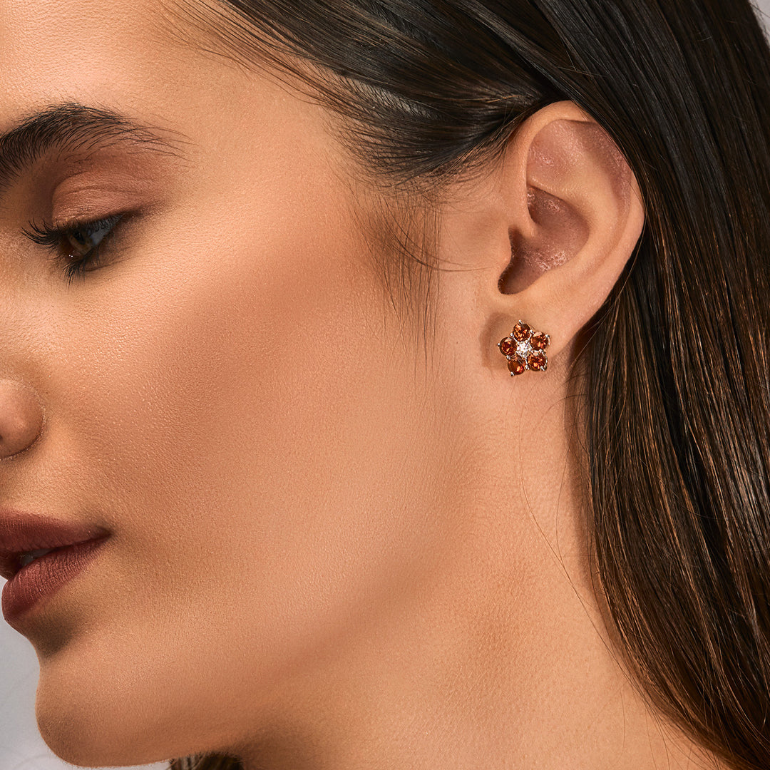 A woman wearing a silver Studs featured with Red Garnet and Cubic Zirconia.